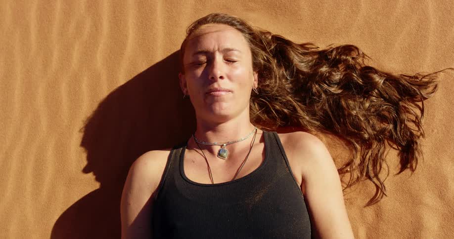 A woman is laying down in the sand