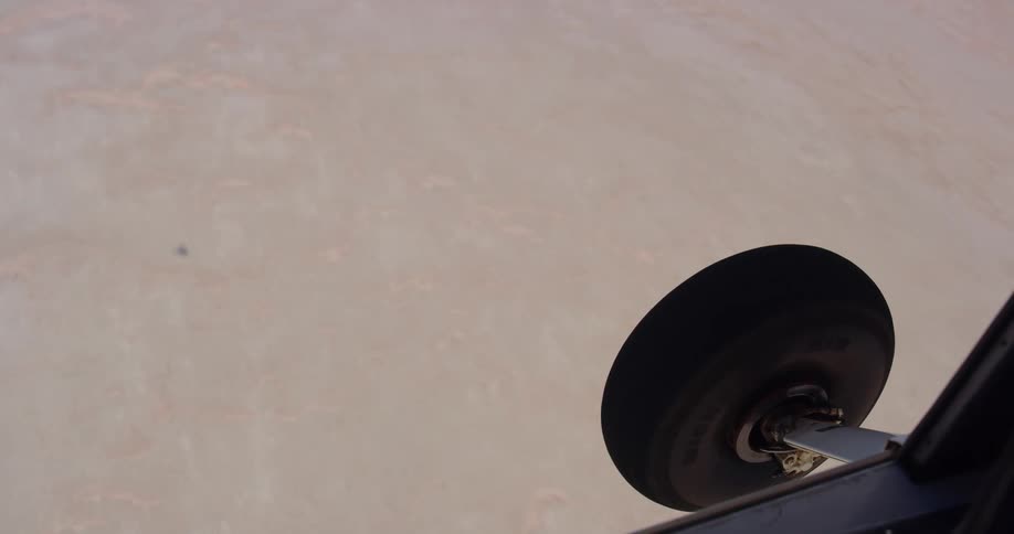 A plane is flying high off the ground above a desert