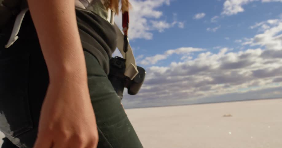 A female photographer walks through the desert on a sunny day