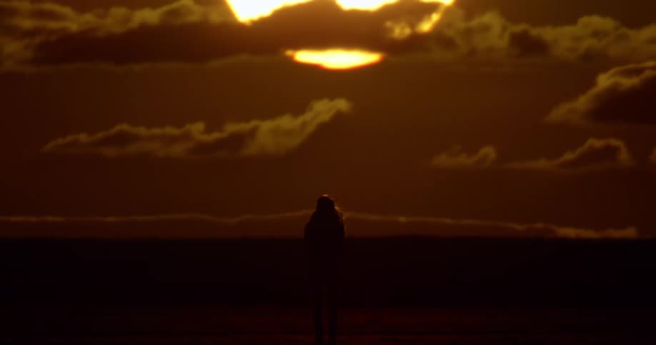 A woman in silhouette in front of the setting sun