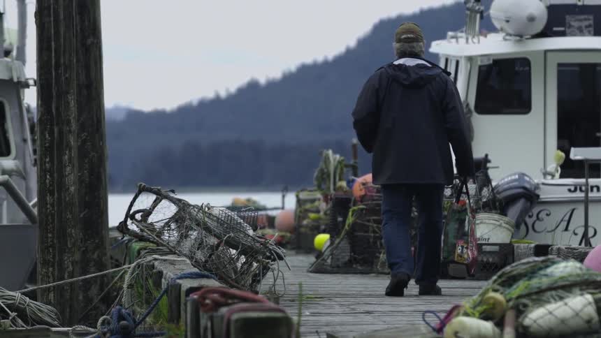 A man walks over to a ship docked by the pier