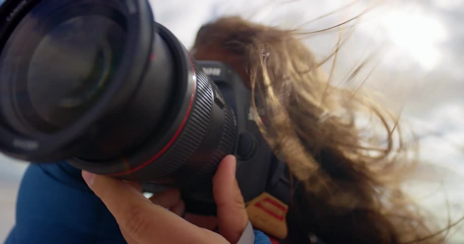 A woman is taking photographs with a long lens in blowing wind