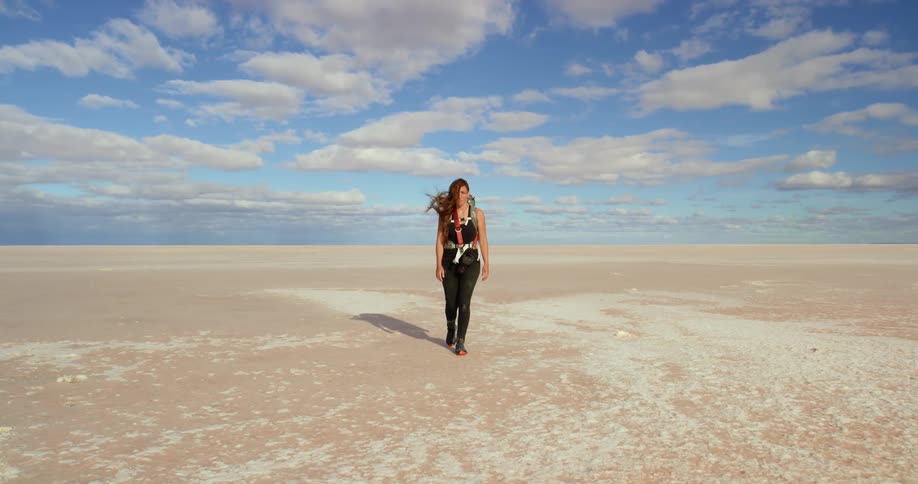 A woman walks towards us in a vast desert