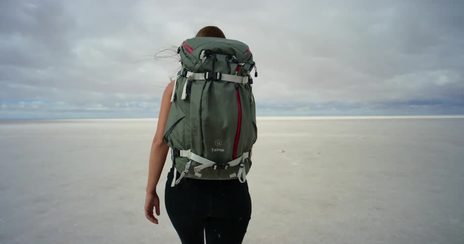 A woman is hiking through a vast desert