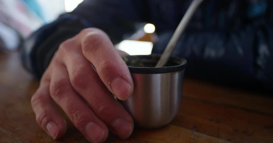 A person has a cup of mate tea in his hand