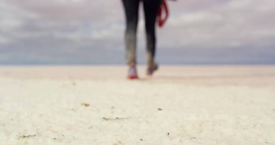 A person picks up their camera in the sand