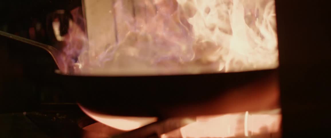 Fire burns in a pan held over the stove