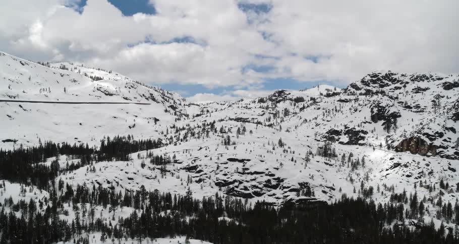 An aerial view of snowy mountains on a cloudy day