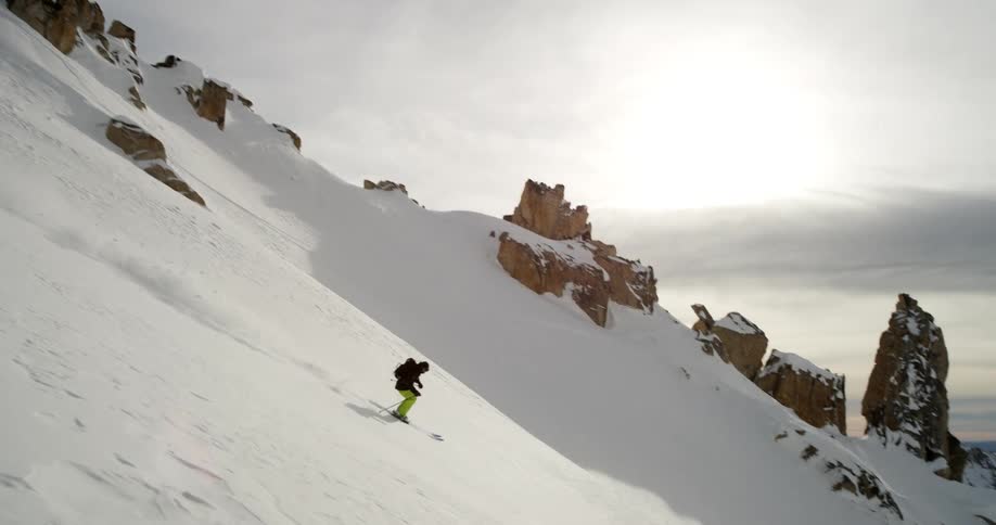 A skier glides down a snowy mountainside on a winter day