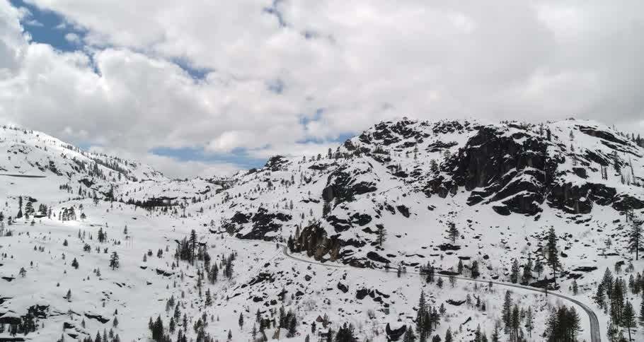 A road winding through a snowy mountain landscape on a cloudy day