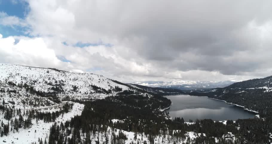 Clouds floating above a lake surrounded by snowy mountains on a winter day