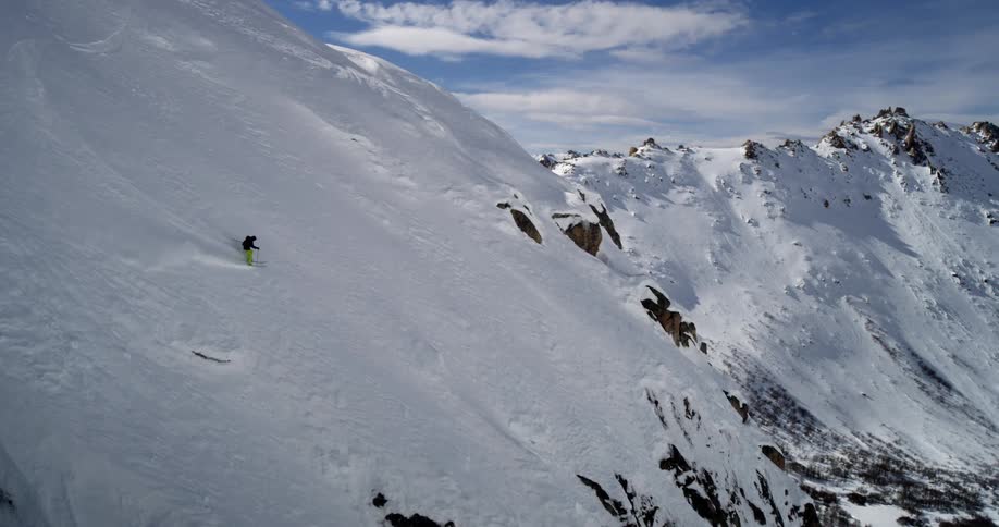 A person skis down a steep snowy mountain face