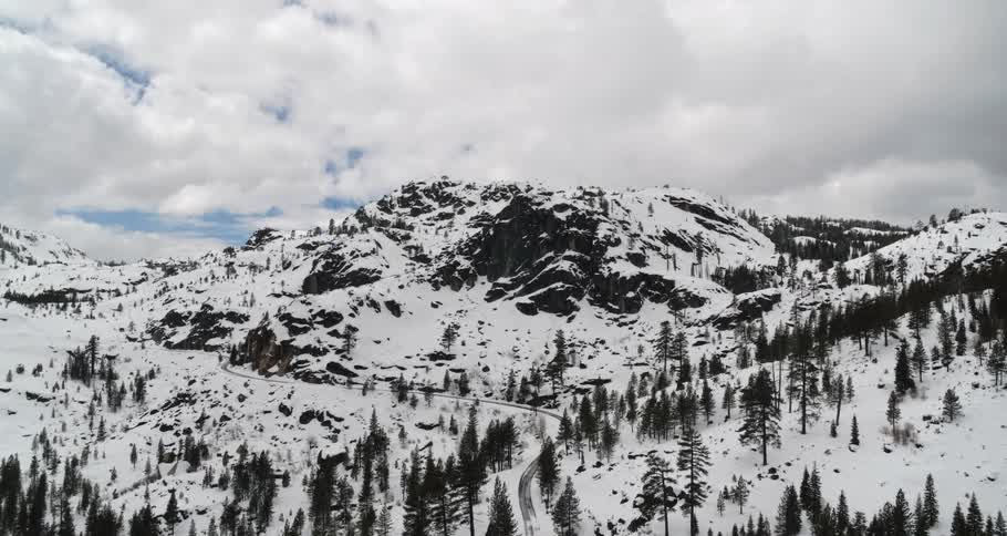 An aerial view of a snowy mountain landscape on a cloudy day