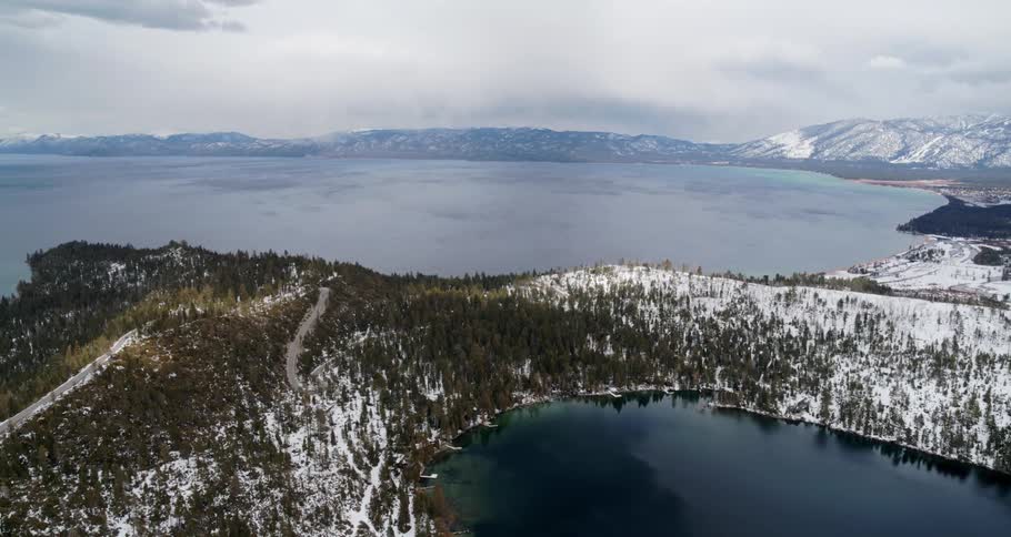 Aerial view of a lake between a mountain range and forest area