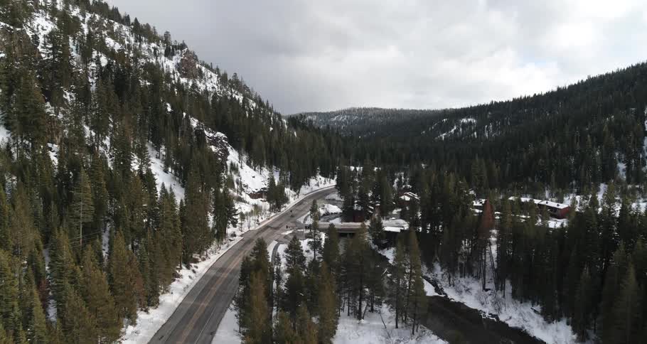 Aerial view of a highway between a snowy mountain and a narrow river