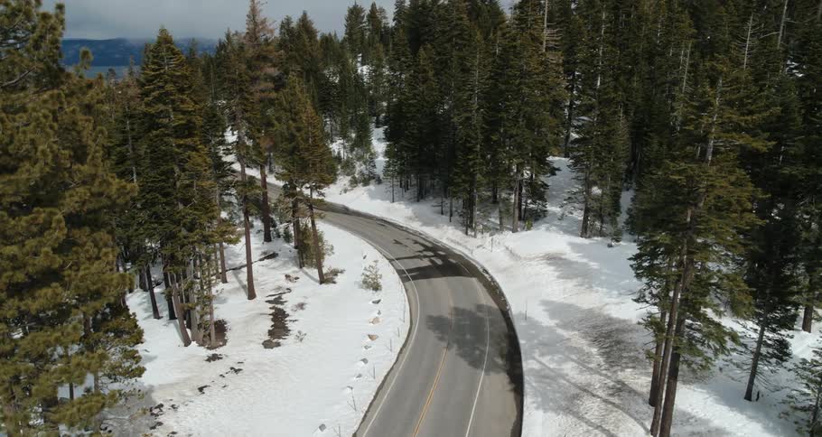 A road with vehicles and people surrounded by snow and trees