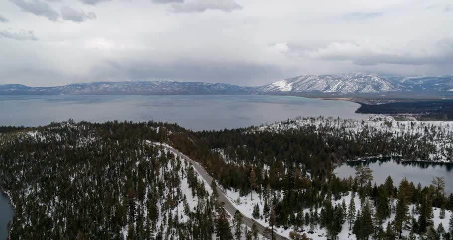 Aerial view snow covered pine forests near a great lake close to the mountains