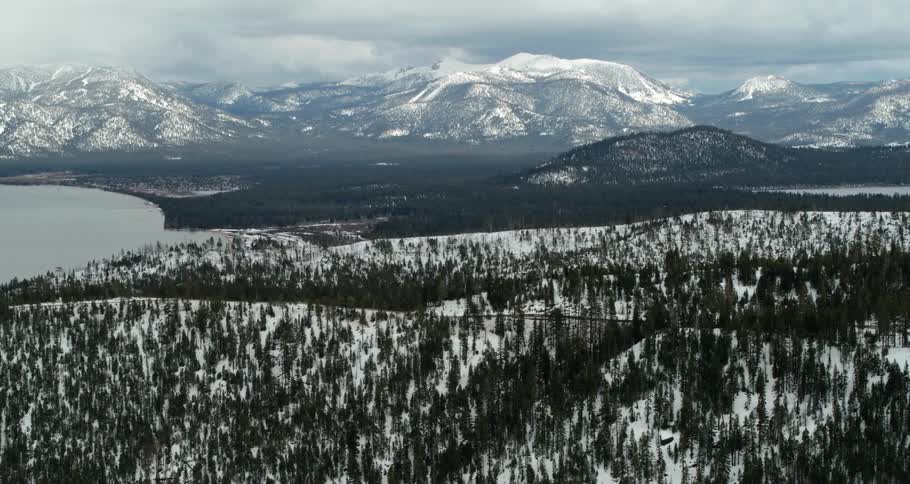 Evergreen hills on the snowy hills surrounding a lake on a sunny day