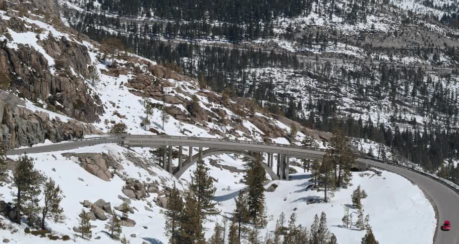 A vehicle travels along a road across a snowy mountain ridge