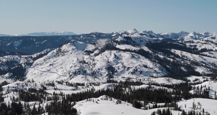A mountain range and surrounding forest are covered in a blanket of snow