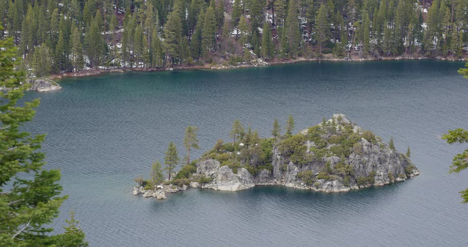 A mountain lake covered in rock and pine trees on a winter day