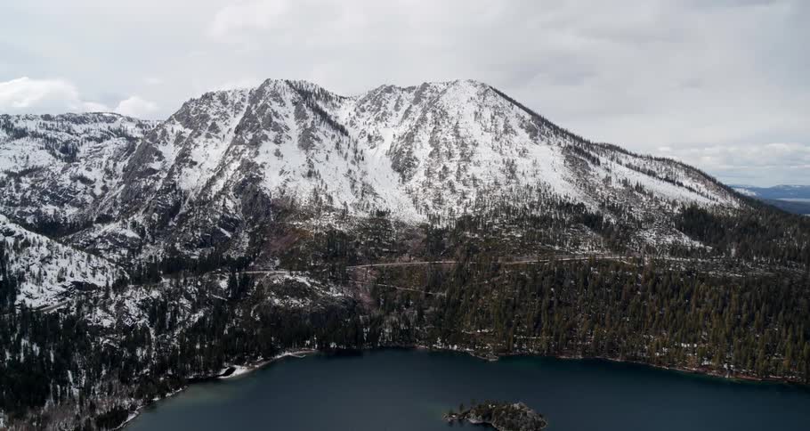 Aerial view of a lake in front of a snow covered forest