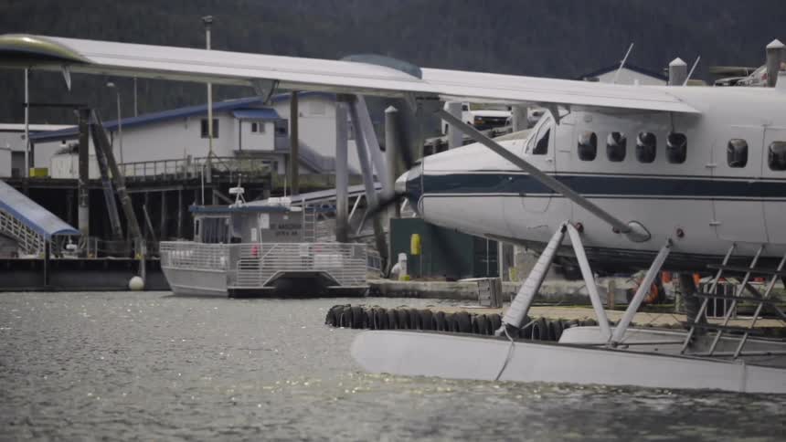 Sea plane on some still water near a dock with its propeller spinning