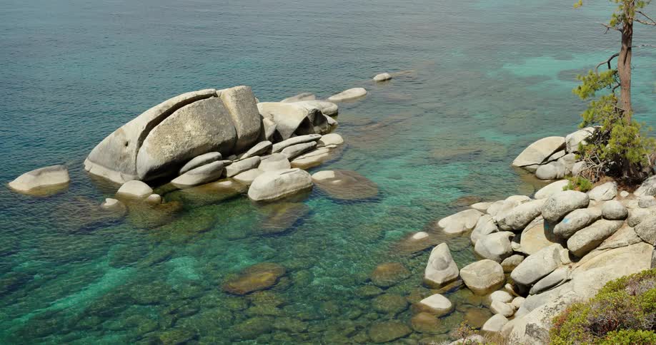 Water ripples around rocks and boulders on a lake on a summer day