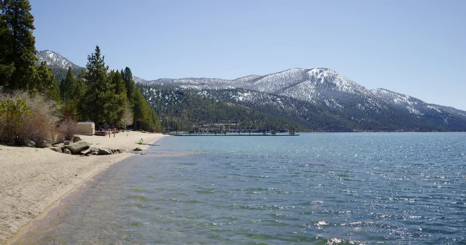 A landscape view of the water and shore with mountains in the distance