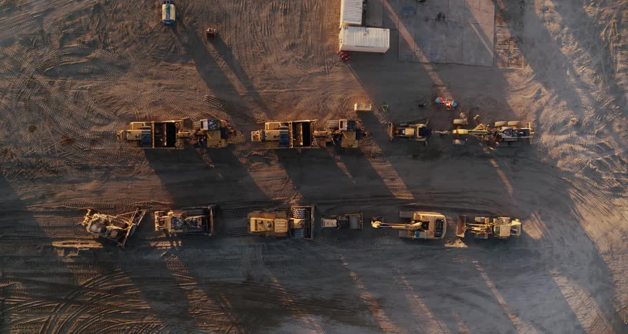 Car drives away from constructions site where construction equipment is parked in rows