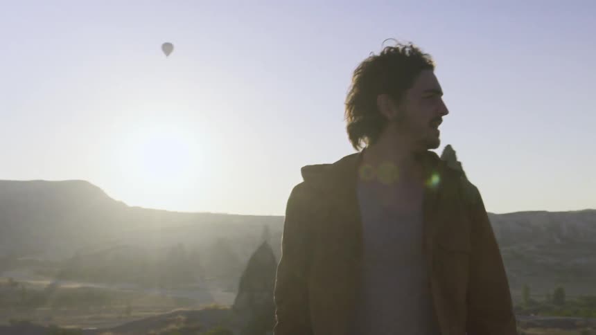 A man stands in a natural setting and turns around