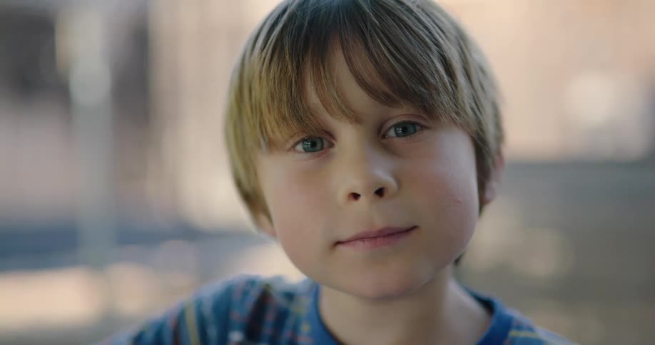 A boy looks up from painting to smile into the camera
