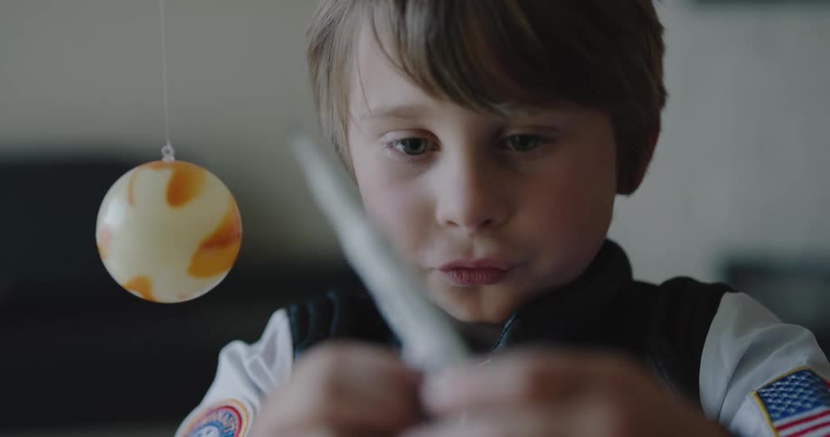 A young boy plays with a toy rocket ship and shuttle which he pretends collide in outer space