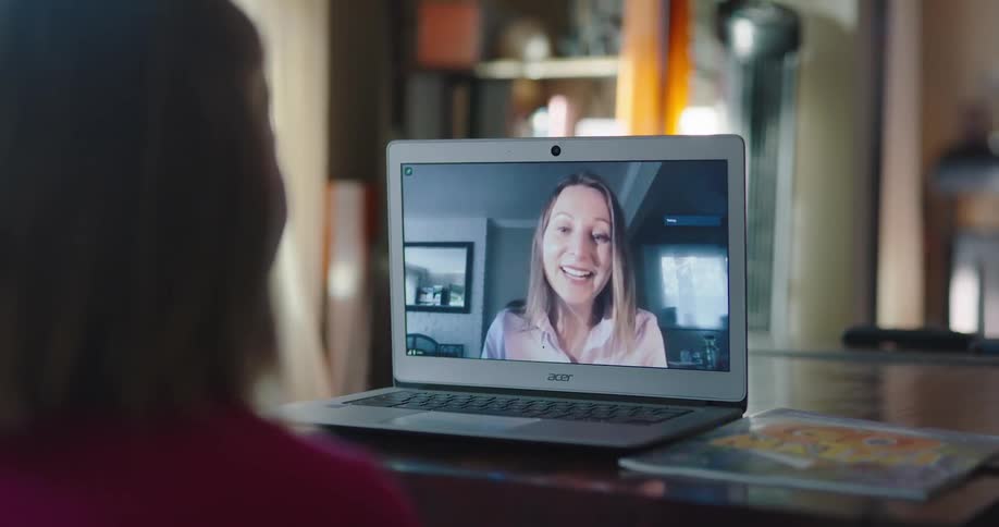 Women talk and laugh via video on their laptop at home