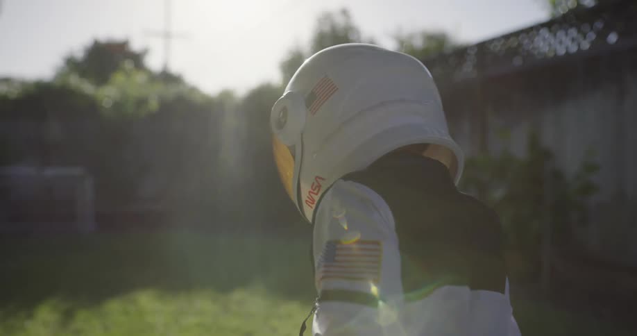 A child in an astronaut costume walks in the yard