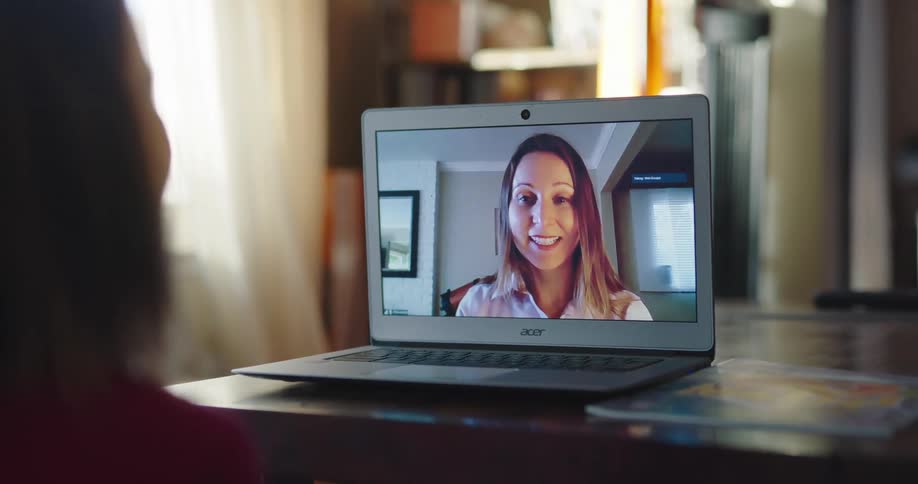 A pair of women talk to one another through video chat on a laptop