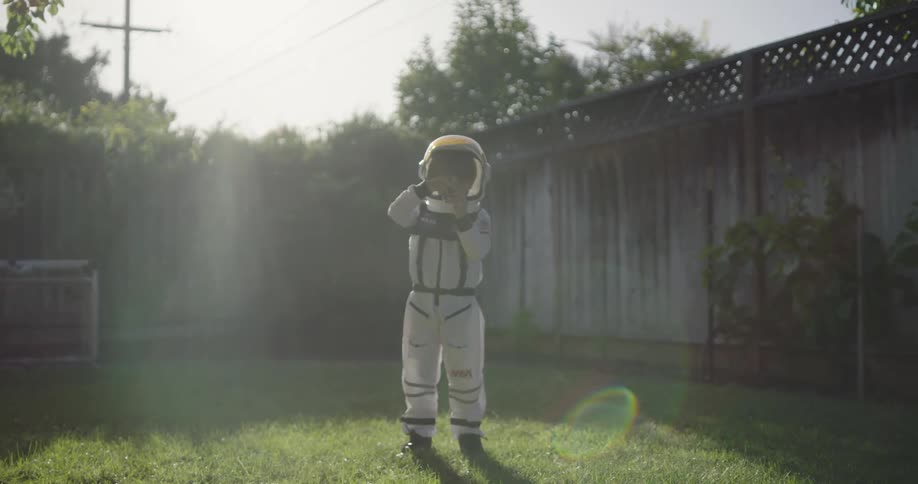 A child is wearing an astronaut costume in the yard