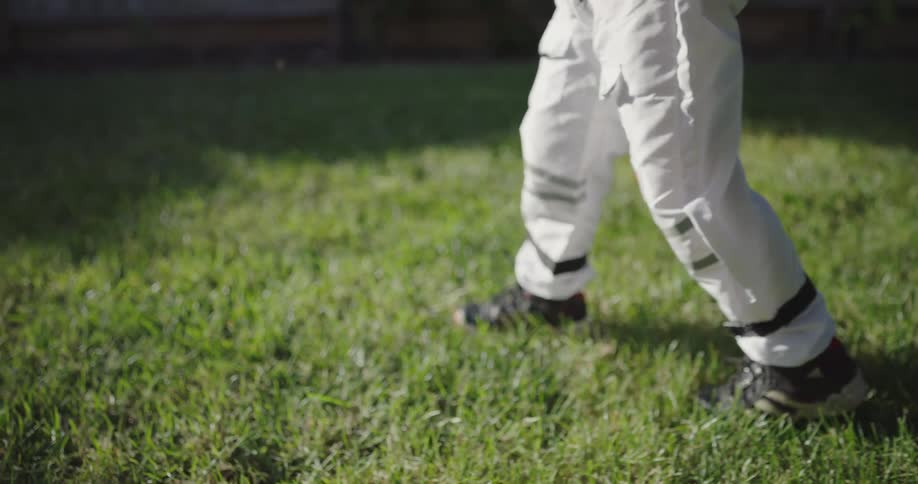 A young boy wearing a nasa astronaut costume pretends he is walking on the surface of the moon while in his backyard