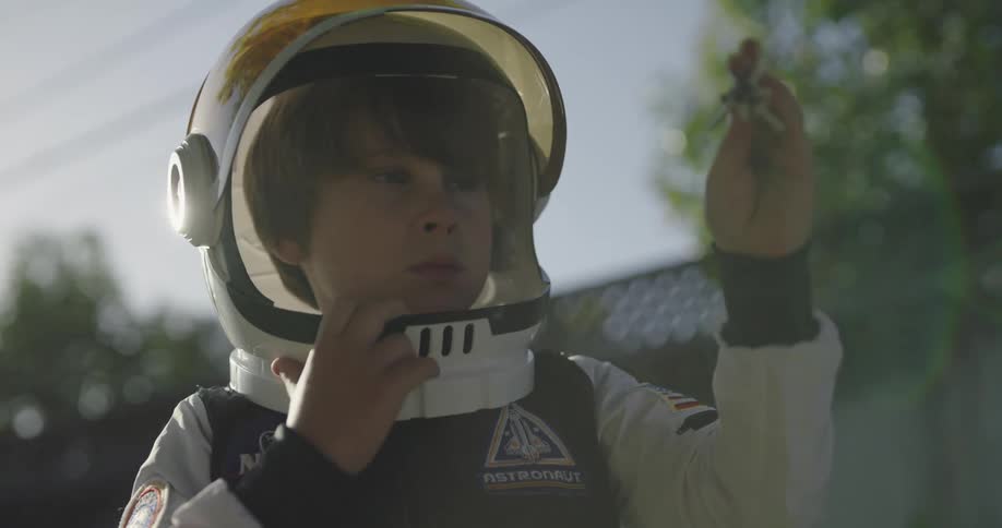 Young boy wearing a space suit plays with a toy rocketship