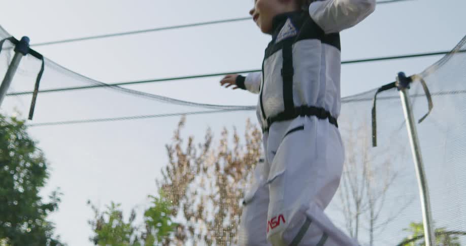 A young boy is happily jumping on a trampoline outdoors