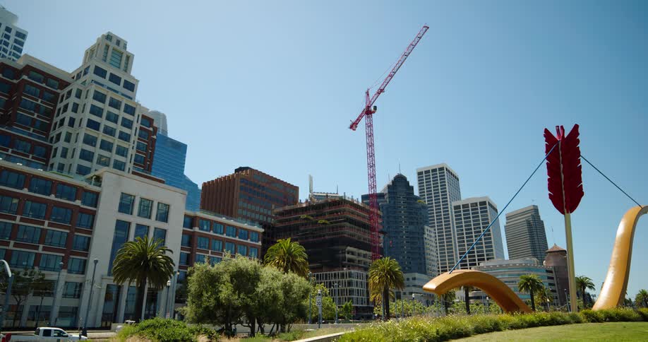 A construction crane looming over the frame of a building in a metropolis on a sunny day