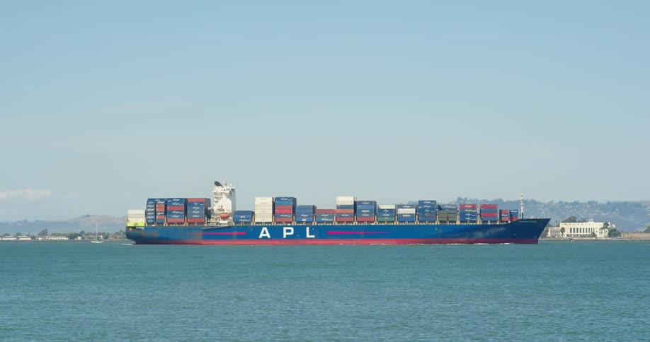 Cargo ship loaded with shipping containers sailing near the coast at day