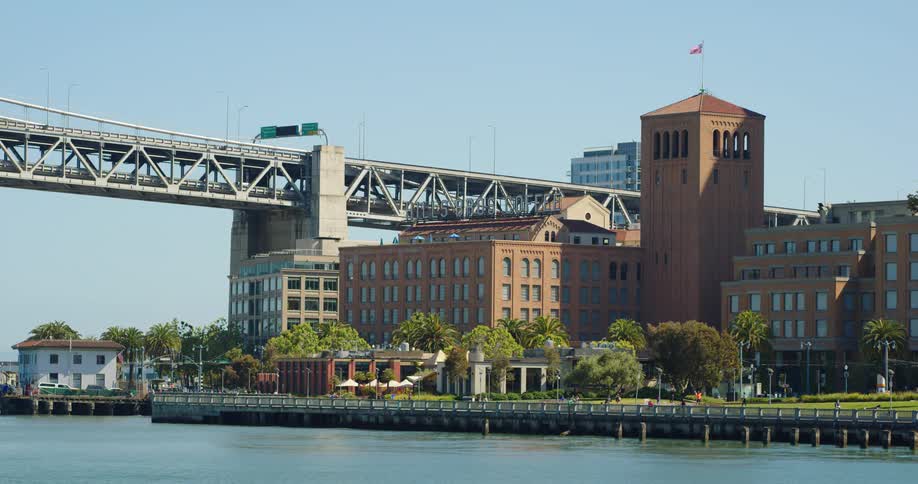 An office building on the waterfront with people and cars and buses going past