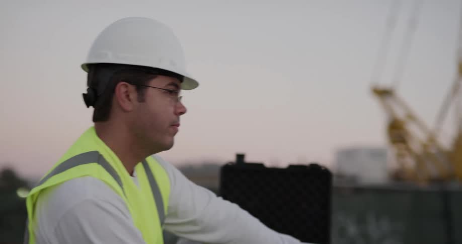 Two men on a construction site look at blue prints and talk