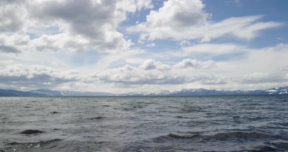 Water flowing on a lake with snowy mountains in the distance