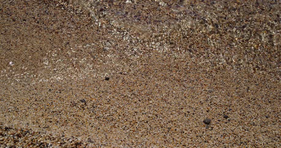 Water lapping onto a brown sandy beach