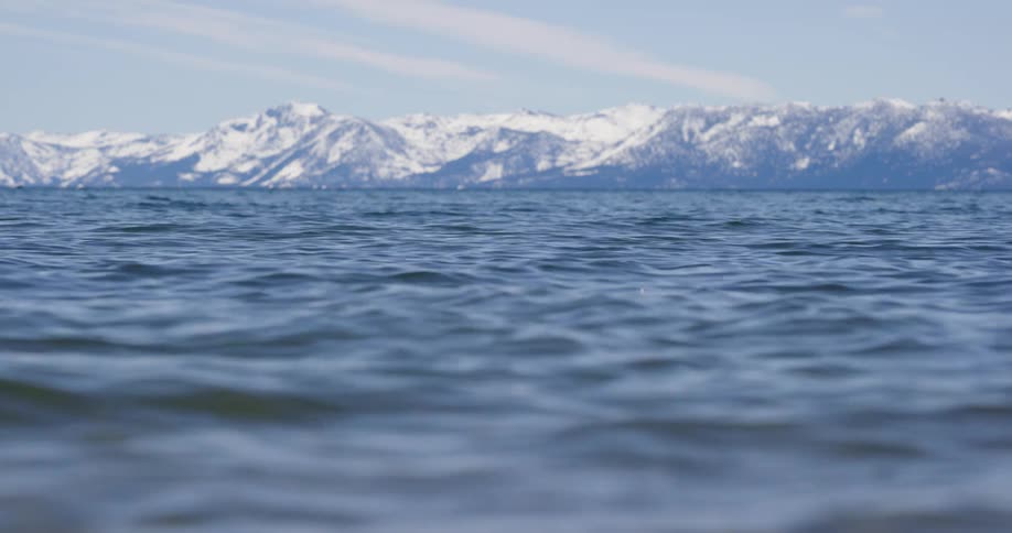 Surface of seawater with snow capped mountains in the background