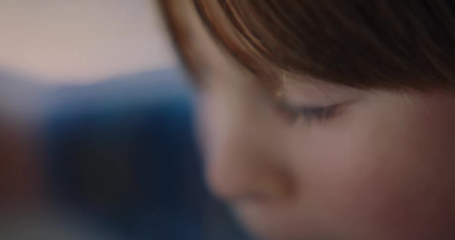 A young boy looks downward as he concentrates on enjoying his task