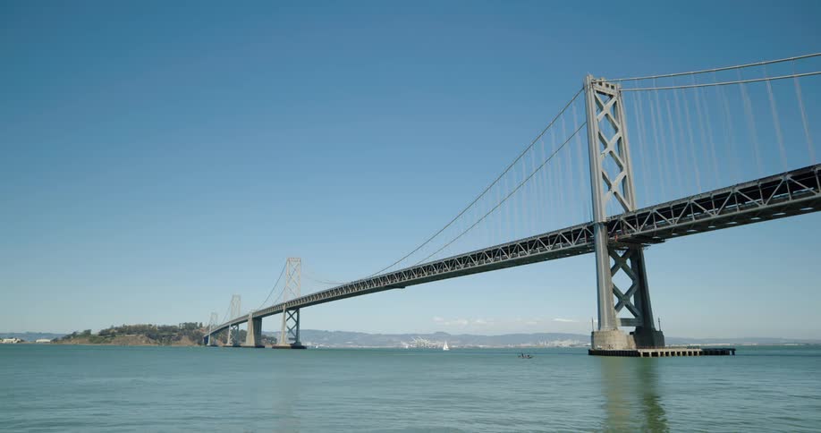 Suspension bridge hanging from steel cables that are supported by towers at each end over a river