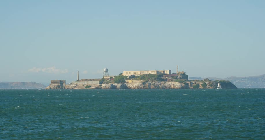 A building on a peninsula jutting out into the ocean where a boat sails slowly by